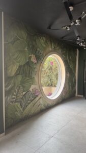 Artistic painted botanical 3D basalt wall surrounding a circular window by MarbleVeins.